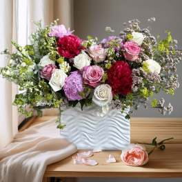 Mixed bouquet of pink, white, and red flowers in a white vase