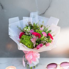 Bouquet of pink roses and green hydrangea wrapped in white paper