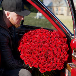 Large bouquet of red roses being held inside a red car