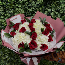 Bouquet of red roses and white hydrangeas wrapped in pink paper