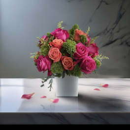 Pink and coral roses arranged in a white square vase