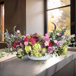 Low floral centerpiece with pink and green blooms in a white bowl.