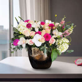 Mixed pink and white flowers arranged in a dark vase