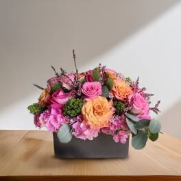 Pink and peach roses arranged in a black rectangular box