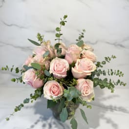 Bouquet of pale pink roses in a dark vase with airy greenery