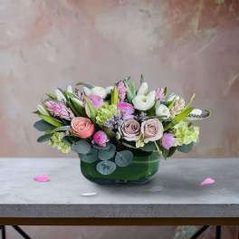 Pink and white mixed flower arrangement in a green glass vase