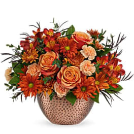 Orange and peach flower arrangement in a patterned vase