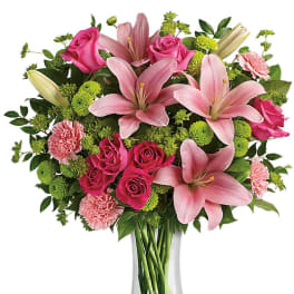 Pink lilies and roses arranged in a clear glass vase