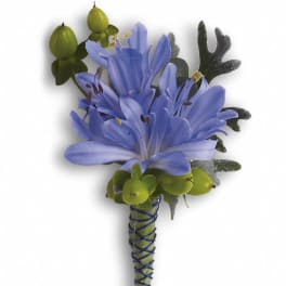 Blue flower boutonniere with green berries and dark foliage