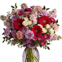 Mixed pink and purple bouquet in a glass vase with red gerbera daisies