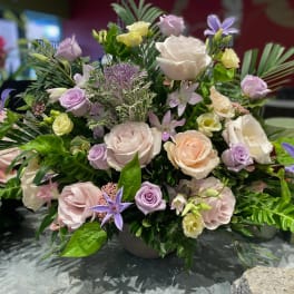 Mixed pastel bouquet with roses and purple star-shaped flowers in a vase