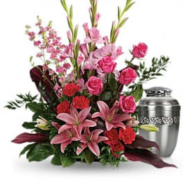 Pink lilies, roses, and carnations arranged beside a silver urn