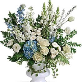 White and blue floral arrangement in a white pedestal vase