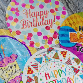 Assorted birthday balloons with colorful confetti and party hat designs
