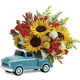 Bouquet of sunflowers and red roses in a turquoise toy truck