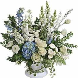 White and blue floral arrangement in a white pedestal vase