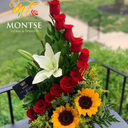 Tall arrangement of red roses, white lilies, and sunflowers in a basket