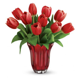 Red tulip bouquet arranged in a red glass vase