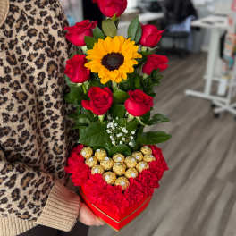 Heart-shaped box with red roses, a sunflower, and chocolates