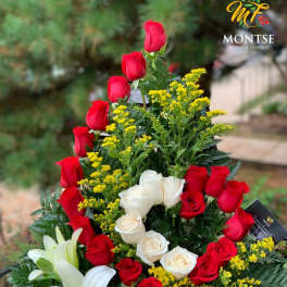 Basket arrangement of red and white roses with white lilies and yellow filler flowers