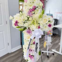 Cross-shaped floral tribute with white and pink flowers on a stand