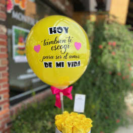 Yellow balloon above a box of yellow roses with a pink ribbon