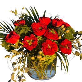 Red roses in a glass vase with greenery and berry accents