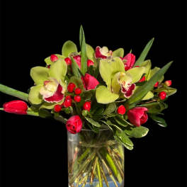 Bouquet of green orchids and red tulips in a clear glass vase
