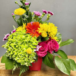 Colorful mixed bouquet in a red container with roses and daisies