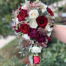 Handheld bouquet of red and white roses with small pink filler flowers