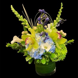 Blue hydrangeas and white calla lilies in a green glass vase