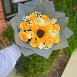 Yellow rose bouquet with a sunflower and baby's breath in gray wrap