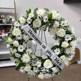 White floral funeral wreath on a stand with a memorial ribbon