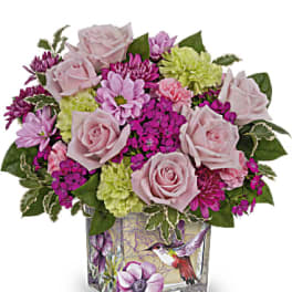 Pink roses and mixed blooms arranged in a square glass vase