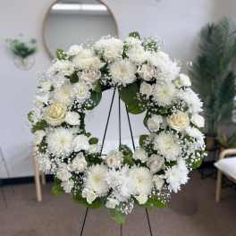 White floral wreath on a stand with roses and chrysanthemums