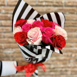 Bouquet of red, pink, and white roses wrapped in black-and-white striped paper