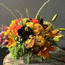 Colorful mixed bouquet in a square glass vase with lilies and mums