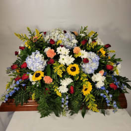 Large casket spray with mixed flowers in red, white, yellow, and blue