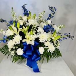 White and blue floral arrangement with a large blue ribbon