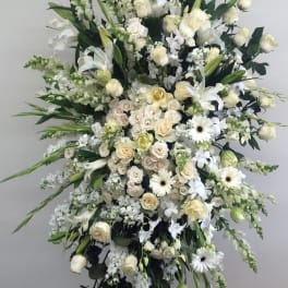 Large white funeral spray with roses, lilies, and gerbera daisies