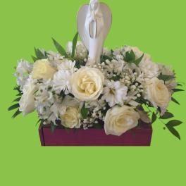 White floral arrangement with a praying angel figurine in a magenta container