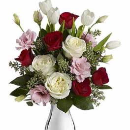 Bouquet of red, white, and pink roses in a clear glass vase