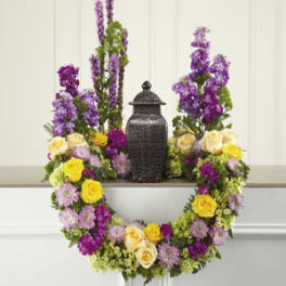 Floral wreath with yellow and cream roses around a dark urn