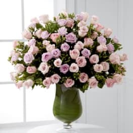 Pink and lavender roses arranged in a green glass vase