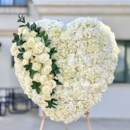 Heart-shaped white floral arrangement with cream roses and greenery