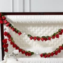 Red rose garlands draped across a white upholstered headboard
