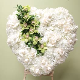 Heart-shaped white floral arrangement with a green orchid accent