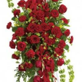 Tall standing spray of red roses and carnations on a white easel