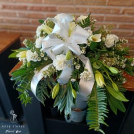 White floral bouquet with lilies, carnations, and a large white ribbon