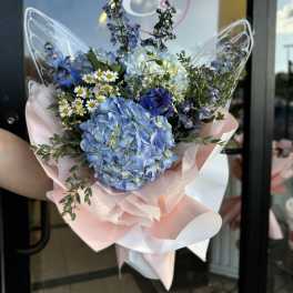 Blue hydrangea bouquet with small white daisies and pink wrapping